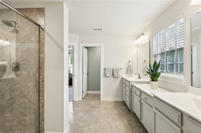 bathroom featuring tiled shower, double vanity, and baseboards