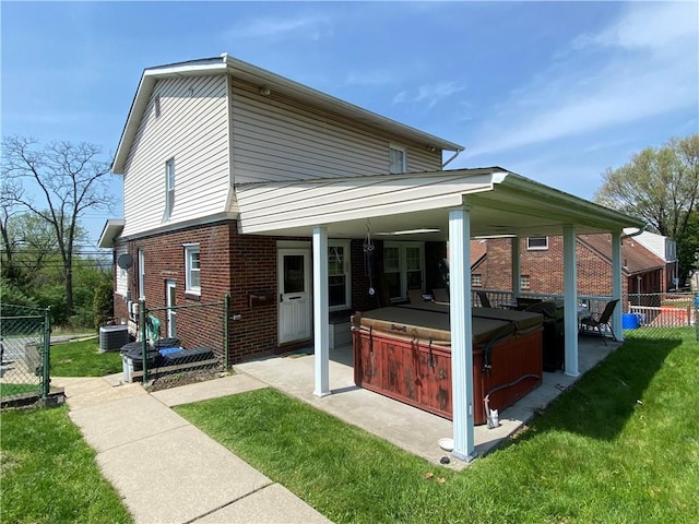back of property featuring a hot tub, brick siding, central air condition unit, and a patio area