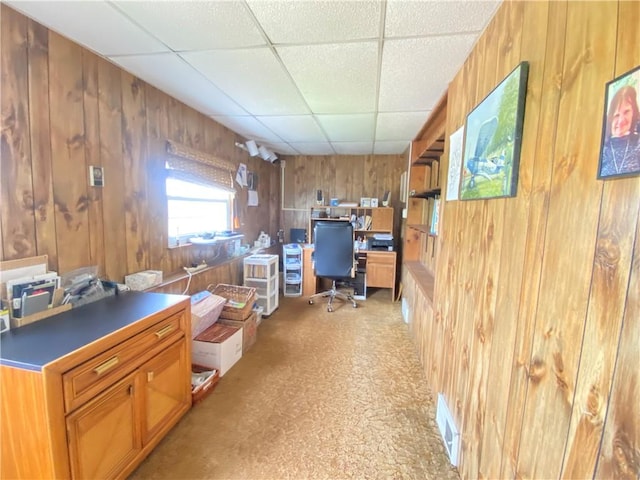 office space with wooden walls and a paneled ceiling