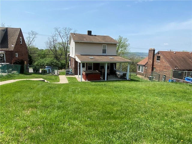 back of property with a hot tub and a patio area