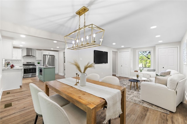dining room with light wood-type flooring, recessed lighting, and baseboards
