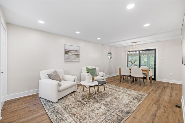 living room with wood finished floors, baseboards, recessed lighting, and a chandelier