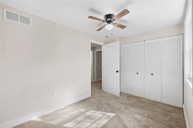 unfurnished bedroom with light carpet, baseboards, a ceiling fan, and a closet