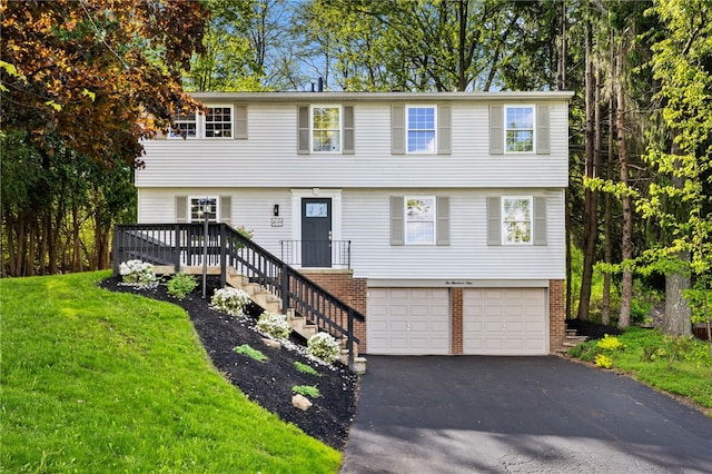 colonial inspired home with asphalt driveway, an attached garage, brick siding, a front yard, and a wooden deck