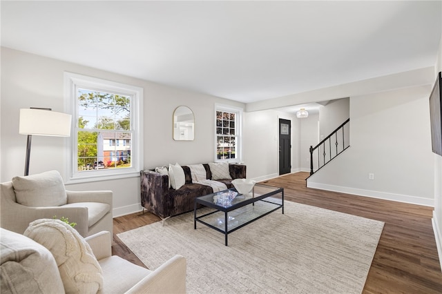 living room with stairs, baseboards, and wood finished floors
