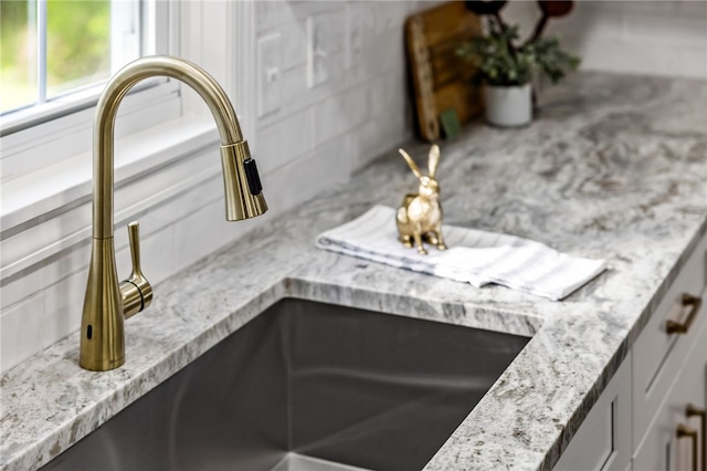 kitchen view of a sink, tasteful backsplash, and light stone counters