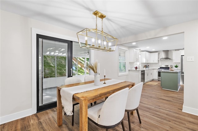 dining space with baseboards, light wood-type flooring, a chandelier, and recessed lighting