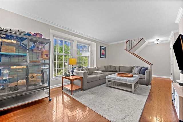living area with crown molding, wood finished floors, baseboards, and stairs