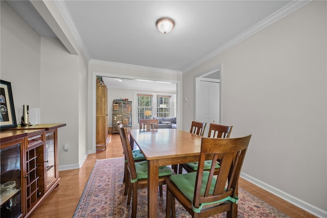 dining space featuring ornamental molding, baseboards, and light wood-style flooring