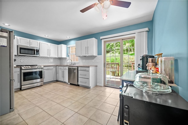 kitchen featuring stainless steel appliances, decorative backsplash, a ceiling fan, light tile patterned flooring, and white cabinets