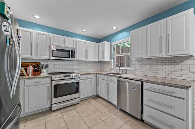 kitchen with appliances with stainless steel finishes, a sink, white cabinets, backsplash, and recessed lighting