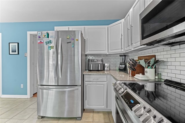 kitchen featuring appliances with stainless steel finishes, light tile patterned flooring, decorative backsplash, and white cabinetry