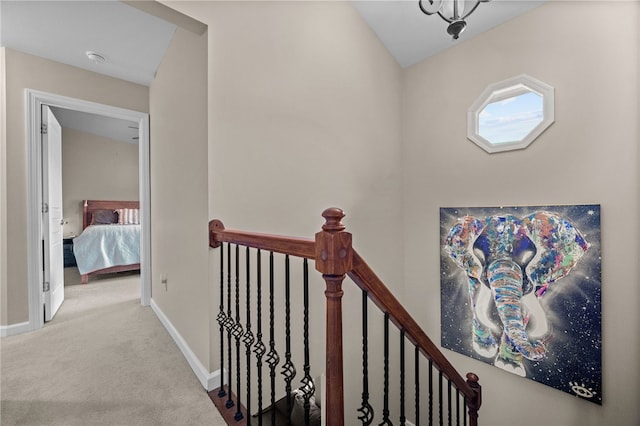 hallway featuring an upstairs landing, carpet, and baseboards