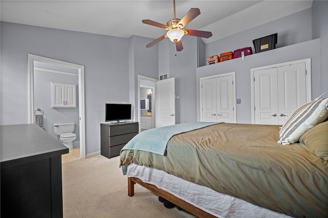 bedroom featuring two closets, high vaulted ceiling, light carpet, baseboards, and ensuite bathroom
