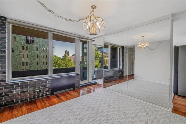 empty room featuring a chandelier, wood finished floors, and baseboards