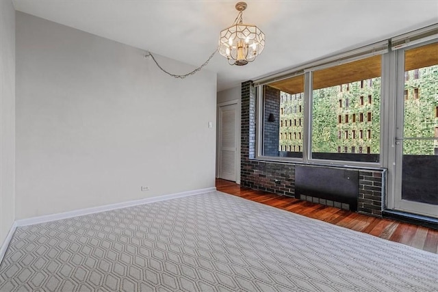 carpeted spare room featuring a chandelier and baseboards