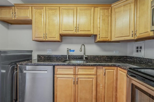 kitchen with stainless steel appliances, a sink, and dark stone countertops