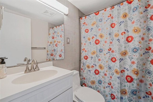 bathroom with tile walls, toilet, vanity, and a shower with curtain
