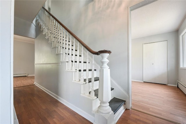 stairs featuring wood finished floors, a baseboard radiator, and baseboards