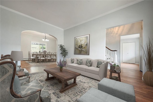 living room with arched walkways, crown molding, wood finished floors, a chandelier, and stairs