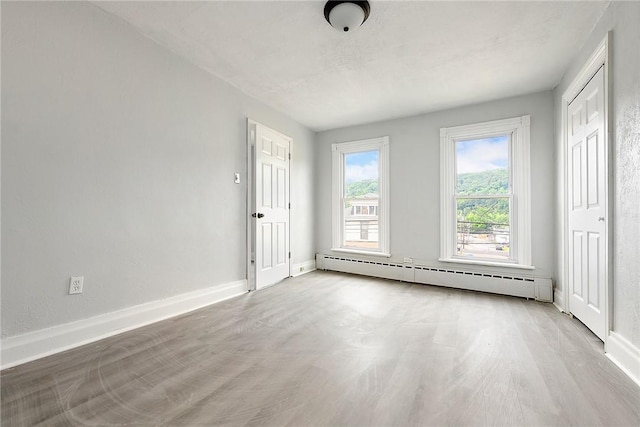 spare room featuring baseboard heating, wood finished floors, and baseboards