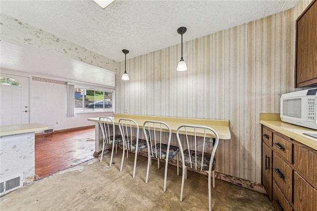 dining room with wallpapered walls and a textured ceiling