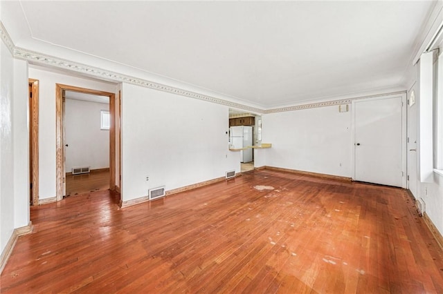 empty room with hardwood / wood-style flooring, ornamental molding, and baseboards