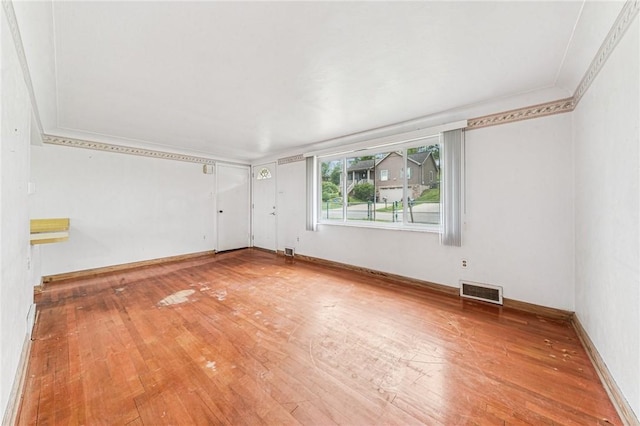 spare room with hardwood / wood-style flooring, baseboards, and ornamental molding