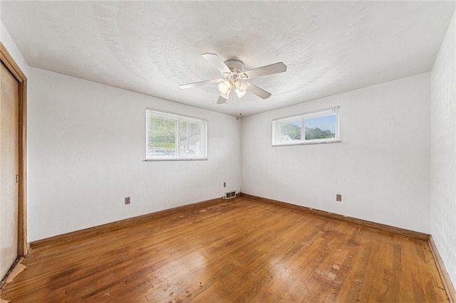 unfurnished bedroom featuring hardwood / wood-style flooring, baseboards, a closet, and a ceiling fan