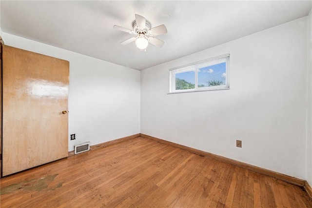 spare room with baseboards, light wood-type flooring, and a ceiling fan
