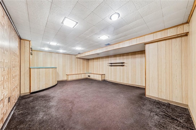 finished below grade area with dark carpet, baseboards, and wooden walls