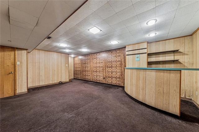 finished basement featuring wood walls and dark carpet