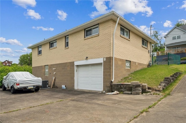 back of house with an attached garage, cooling unit, driveway, and fence
