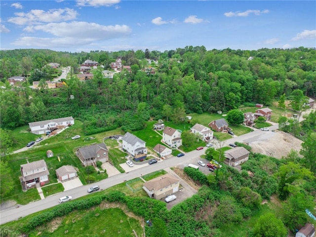 view of property location with nearby suburban area and a forest