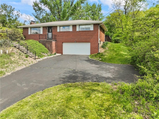 view of front of property with driveway, an attached garage, brick siding, a chimney, and a front lawn