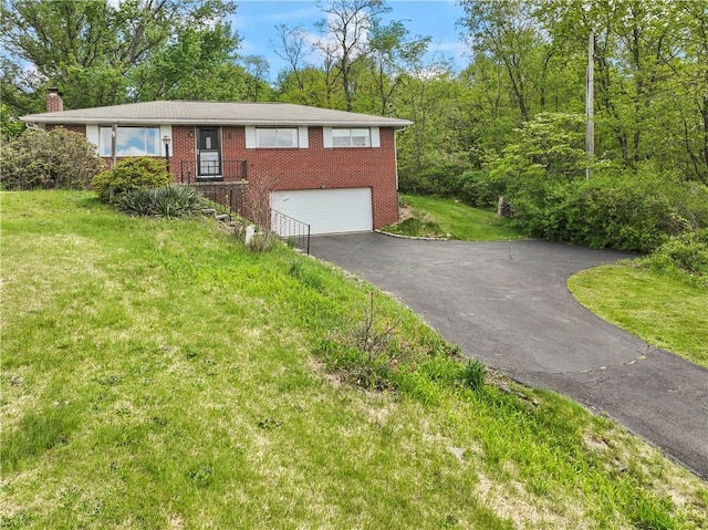 single story home featuring brick siding, driveway, an attached garage, a chimney, and a front lawn