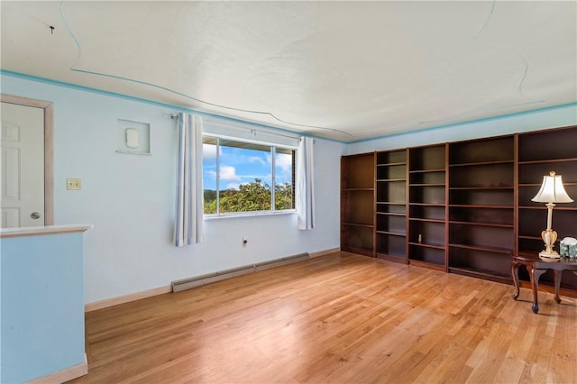 unfurnished room with a baseboard radiator, light wood-type flooring, and baseboards