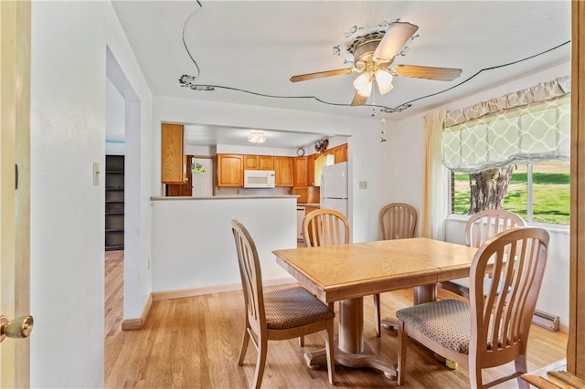 dining area with light wood finished floors, ceiling fan, and baseboards