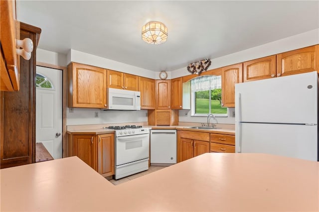 kitchen with white appliances, a sink, and light countertops