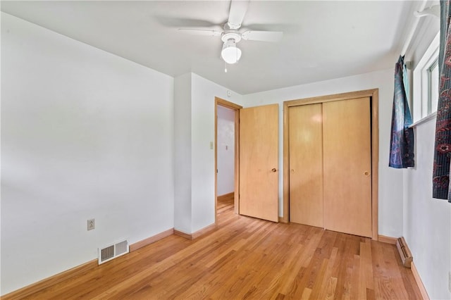 unfurnished bedroom with light wood-style flooring, a closet, baseboards, and ceiling fan