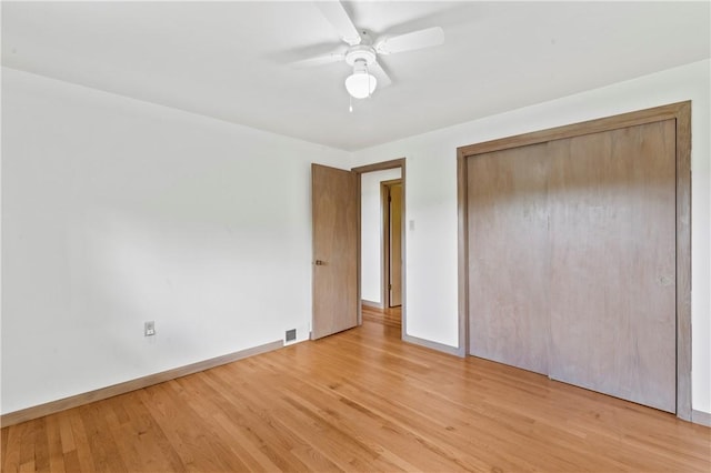 unfurnished bedroom with baseboards, light wood-style floors, a closet, and a ceiling fan