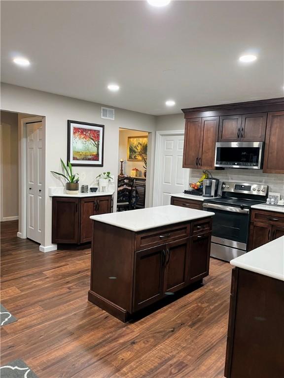1016 Timberwood Ct, Murrysville, PA 15668 - kitchen with appliances with stainless steel finishes, light countertops, dark brown cabinetry, decorative backsplash, and a center island