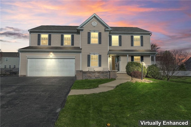 traditional-style home with a garage, asphalt driveway, a yard, and covered porch