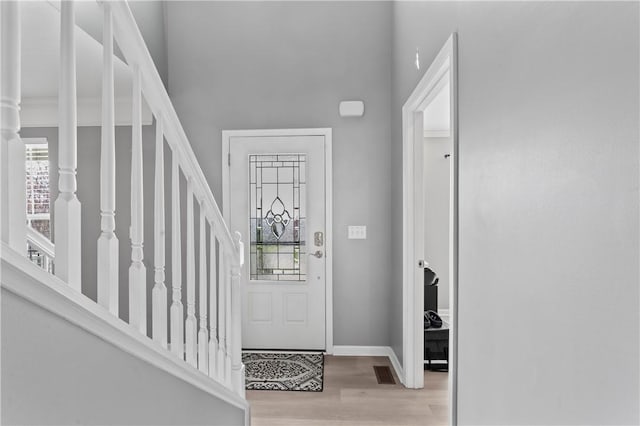 entryway with a high ceiling, light wood-style flooring, and baseboards