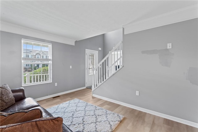 living room with wood finished floors, stairway, baseboards, and crown molding