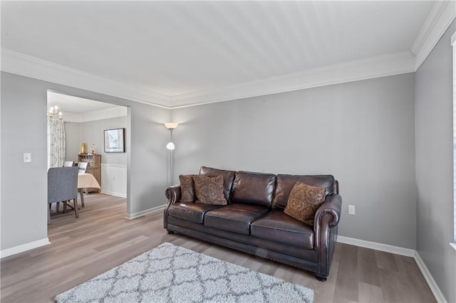 living area with crown molding, wood finished floors, a chandelier, and baseboards