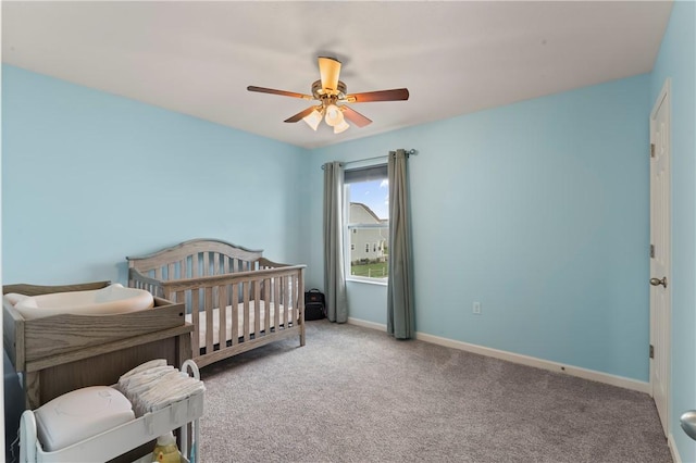 bedroom featuring carpet floors, baseboards, ceiling fan, and a nursery area