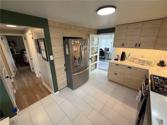 kitchen with stainless steel fridge with ice dispenser, light countertops, decorative backsplash, light tile patterned flooring, and modern cabinets