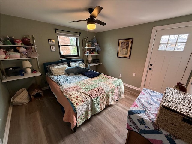 bedroom with light wood-style floors, a ceiling fan, and baseboards