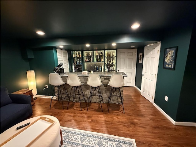 indoor wet bar featuring baseboards, dark wood finished floors, and recessed lighting